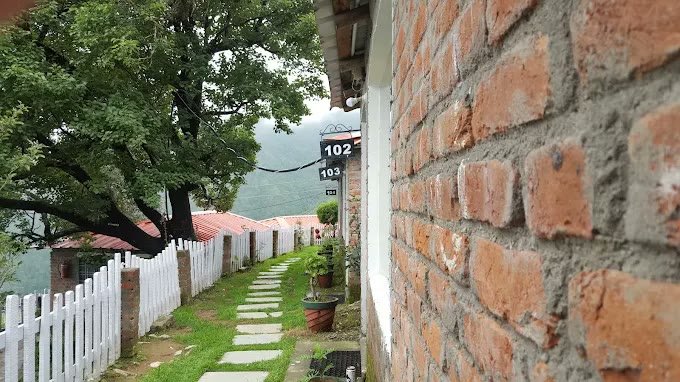 Red-brick cottage walkway with rooms 102 to 104 plaques