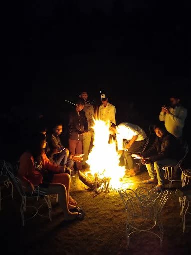 Group of guests enjoying evening bonfire gathering at Kanatal Camp
